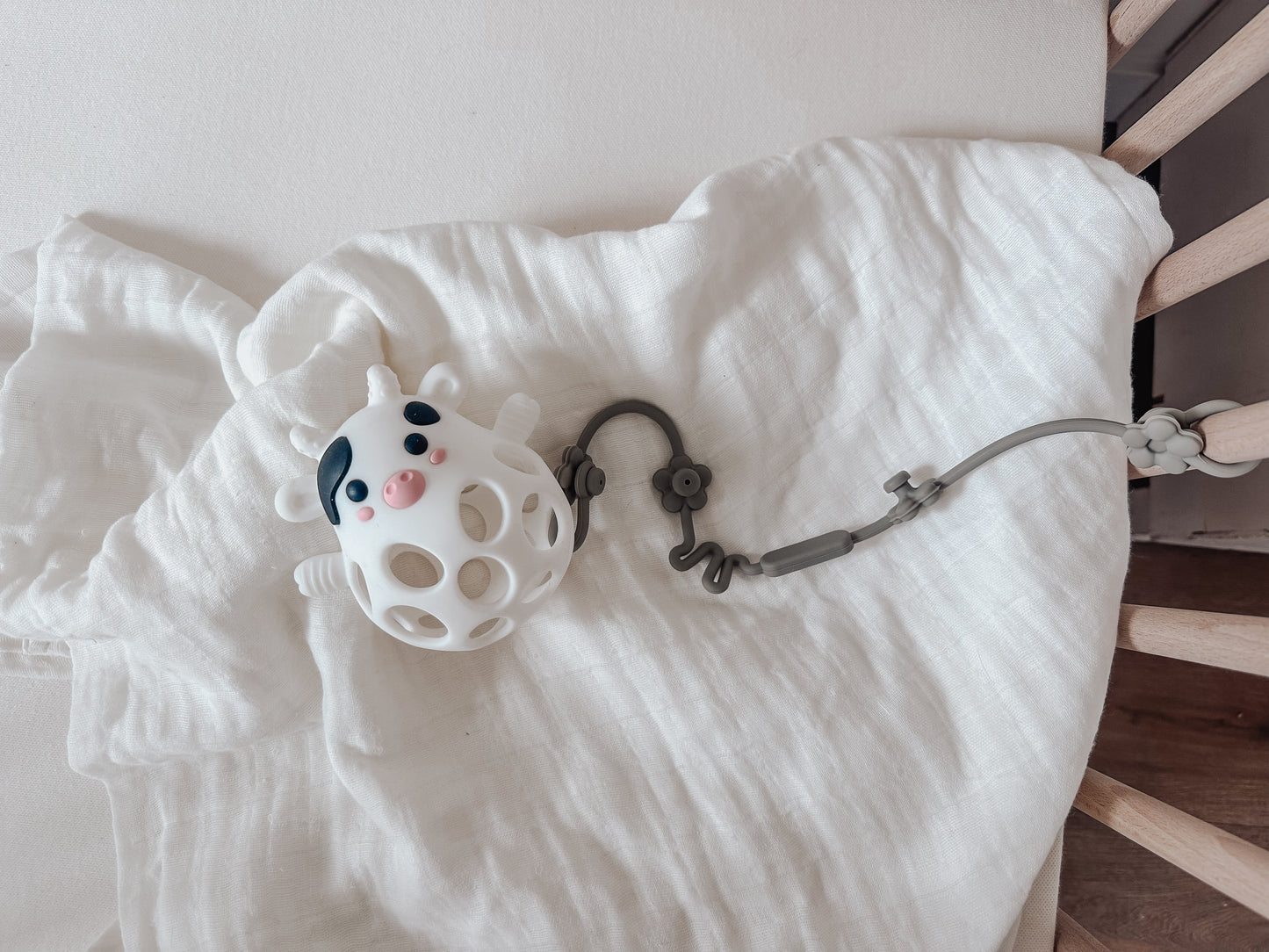 millie the cow teething toy placed on a swaddle blanket in a crib